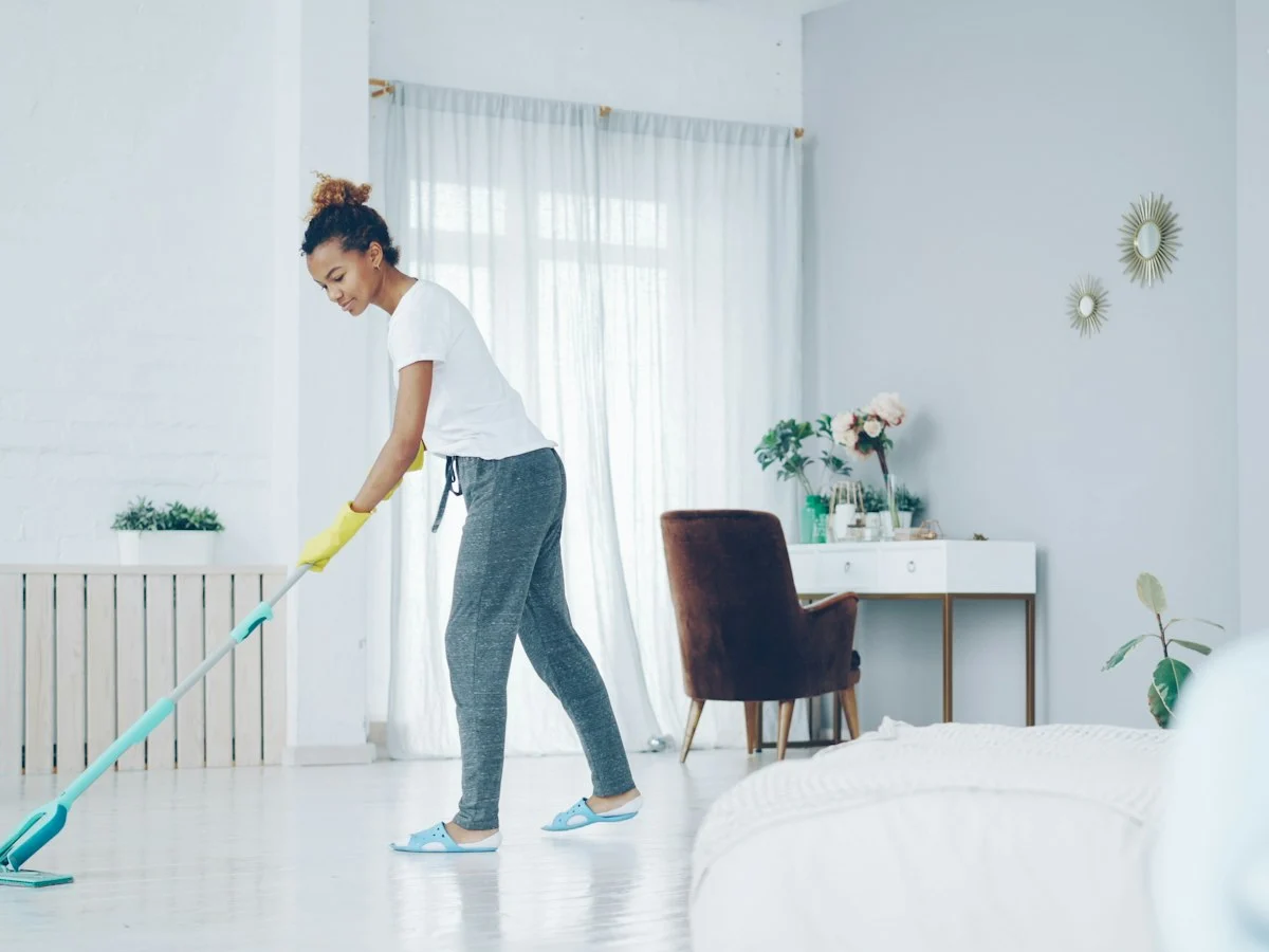 Cleaner mopping the floor of a bright, tidy living room