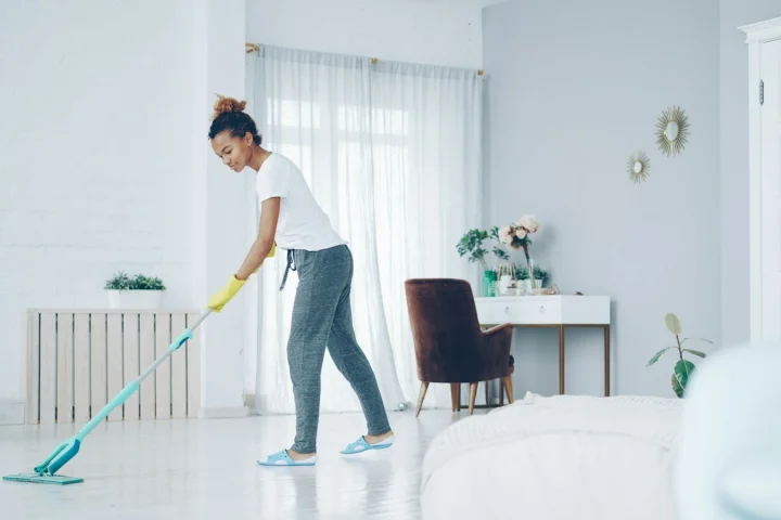 Cleaner mopping the floor of a bright, tidy living room