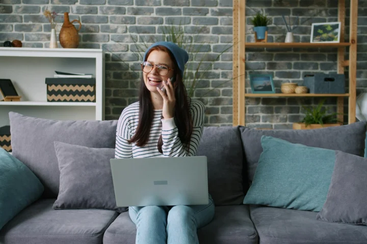 Customer talking on the phone while using a laptop at home