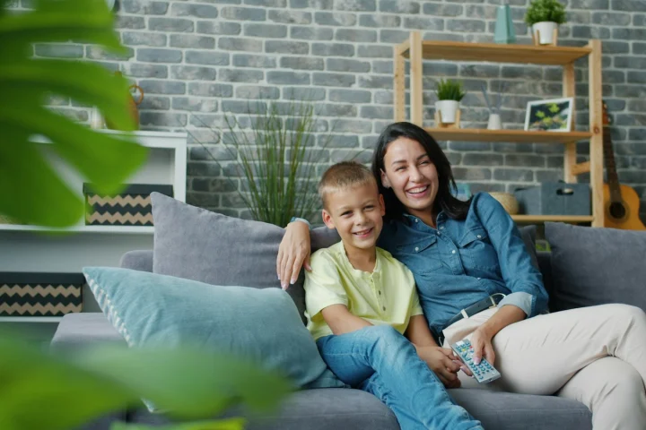 Parent and child relaxing together on the sofa at home