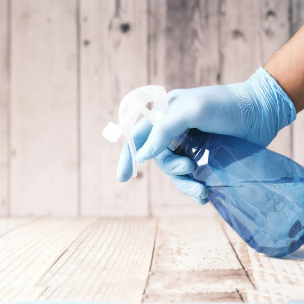 Gloved hand holding a blue spray bottle