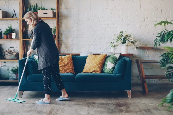 Cleaner mopping a living room floor during a home cleaning