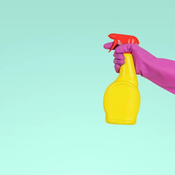 Gloved hand holding a spray bottle of cleaning solution